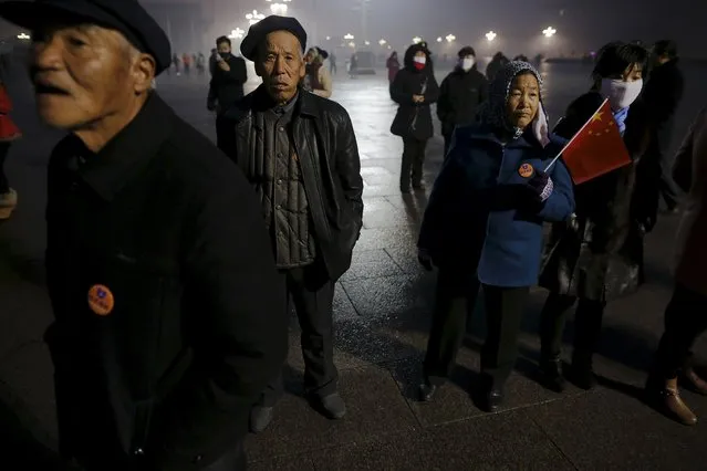 People gather before dawn at the Tiananmen Square for a flag-raising ceremony amid heavy smog, after the city issued its first ever "red alert" for air pollution, in Beijing December 9, 2015. (Photo by Damir Sagolj/Reuters)