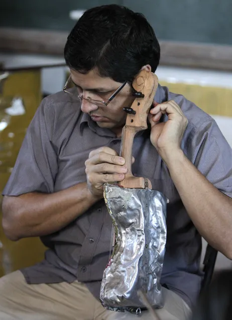 Director of the Orchestra of Recycled Instruments of Cateura, Favio Chavez, tunes one of the orchestra's instruments made of recycled a recycled paint can at the Vy'a Renda education center in Cateura, near Asuncion, May 8, 2013. (Photo by Jorge Adorno/Reuters)