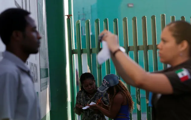 An immigration officer takes a picture of a migrant as others fill a form outside the immigration office to fix their papers and continue their journey in Tapachula, Chiapas, Mexico November 16, 2016. (Photo by Carlos Jasso/Reuters)