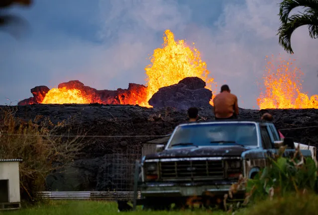 Several residents of Leilani Estates watch fountaining at fissure 7 from the bed of an abandoned vehicle in their friend's backyard,Pahoa, Hawaii, USA, 26 May 2018 (issued 27 May 2018). More homes have been consumed as the eruptions progress. (Photo by Bruce Omori/EPA/Paradise Helicopters)