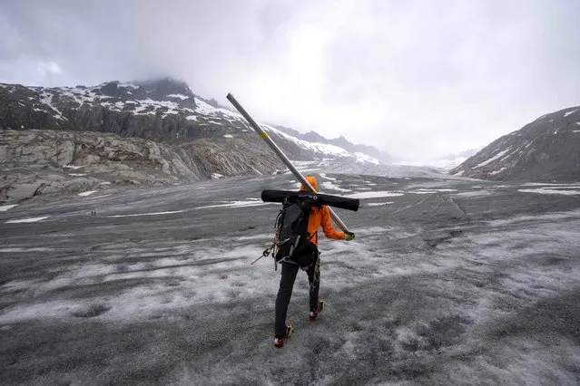 ETH (Swiss Federal Institute of Technology) glaciologist and head of the Swiss measurement network “Glamos”, Matthias Huss, walks up to the Rhone Glacier near Goms, Switzerland, Friday, June 16, 2023. (Photo by Matthias Schrader/AP Photo)