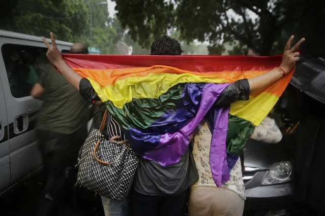Gay rights activists hold a wet flag as they celebrate amid heavy downpour after the country's top court struck down a colonial-era law that made homosexual acts punishable by up to 10 years in prison, in New Delhi, India, Thursday, September 6, 2018. The court gave its ruling Thursday on a petition filed by five people who challenged the law, saying they are living in fear of being harassed and prosecuted by police. (Photo by Altaf Qadri/AP Photo)