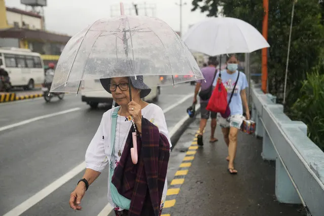 Women uses umbrella during enhanced rains brought about by Typhoon Doksuri on Thursday, July 27, 2023, in Marikina city, Philippines. (Photo by Aaron Favila/AP Photo)