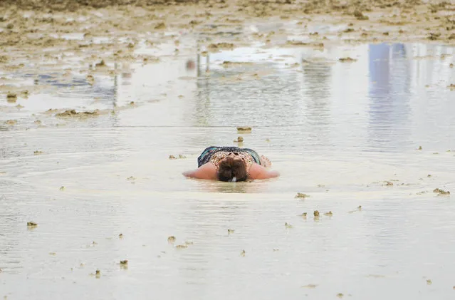 A Burning Man attendee lies down in the mud and water at the event in Black Rock City, in the Nevada desert, after a rainstorm turned the site into mud on September 2, 2023. (Photo by Trevor Hughes/USA Today Network via Reuters)