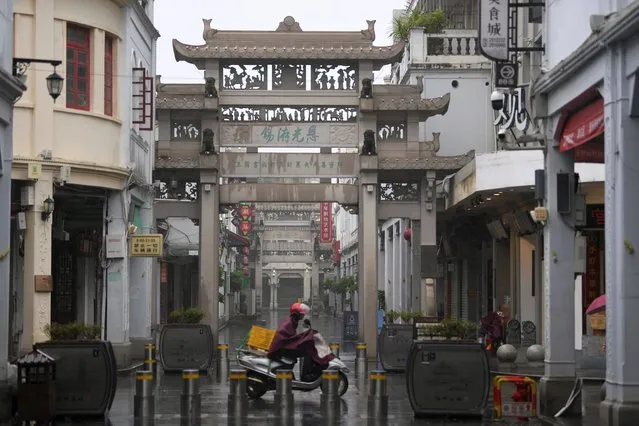 In this photo released by Xinhua News Agency, a motorist rides past a traditional gateway on a wet day in Paifang Street in the city of Chaozhou in southern China's Guangdong province on Tuesday, September 5, 2023. A few people have been killed and thousands forced to evacuate by floods brought by tropical storm Haikui in China’s southeastern coastal Fujian province, local authorities reported Wednesday. (Photo by Deng Hua/Xinhua via AP Photo)