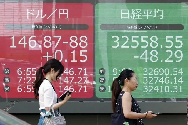 People walk in front of an electronic stock board showing Japan's Nikkei 225 index and U.S. dollar/Japanese yen exchange rate at a securities firm Monday, September 11, 2023, in Tokyo. Stock prices were mostly higher in Asia on Monday as investors awaited U.S. inflation figures and China’s latest economic data. (Photo by Eugene Hoshiko/AP Photo)