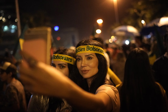 Supporters of Jair Bolsonaro pose for a “selfie” as they celebrate in front of his residence in Rio de Janeiro, Brazil, Sunday, October 28, 2018, after he was declared the winner of the runoff election. Brazil's Supreme Electoral Tribunal declared the far-right congressman the next president of Latin America's biggest country. (Photo by Leo Correa/AP Photo)