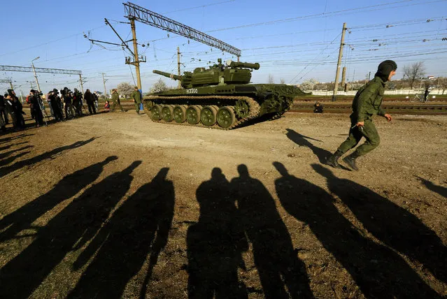 A Russian tank crew member runs in front of his T-72B tank after their arrival in Crimea in the settlement of Gvardeiskoye near Simferopol March 31, 2014. (Photo by Yannis Behrakis/Reuters)