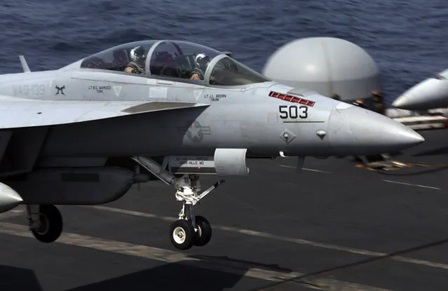 A U.S. military plane lands on the flight deck of the USS Carl Vinson aircraft carrier in the Persian Gulf, Thursday, March 19, 2015. (Photo by Hasan Jamali/AP Photo)