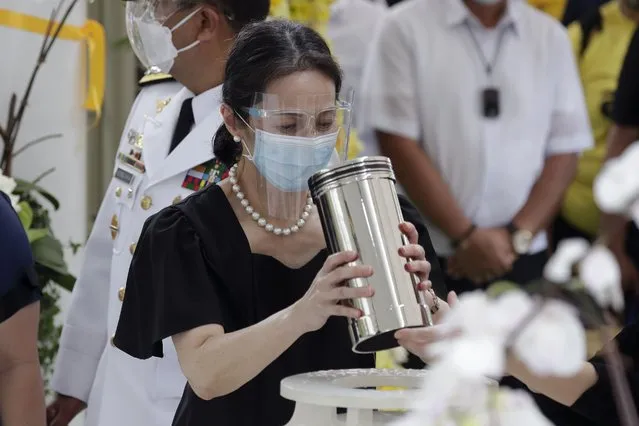 Ballsy Aquino-Cruz holds the urn of her brother former Philippine President Benigno Aquino III before he is placed on the tomb on Saturday, June 26, 2021 at a memorial park in suburban Paranaque city, Philippines. Aquino was buried in austere state rites during the pandemic Saturday with many remembering him for standing up to China over territorial disputes, striking a peace deal with Muslim guerrillas and defending democracy in a Southeast Asian nation where his parents helped topple a dictator. He was 61. (Photo by Aaron Favila/AP Photo)