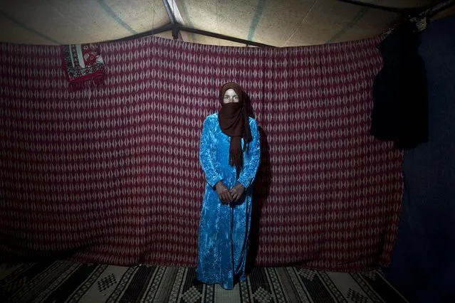 In this Monday, March 16, 2015 photo, Syrian refugee Thuraya Nayif, 40, a mother of seven children in her second month of pregnancy, poses for a photograph inside her tent at an informal settlement near the Syrian border, on the outskirts of Mafraq, Jordan. (Photo by Muhammed Muheisen/AP Photo)