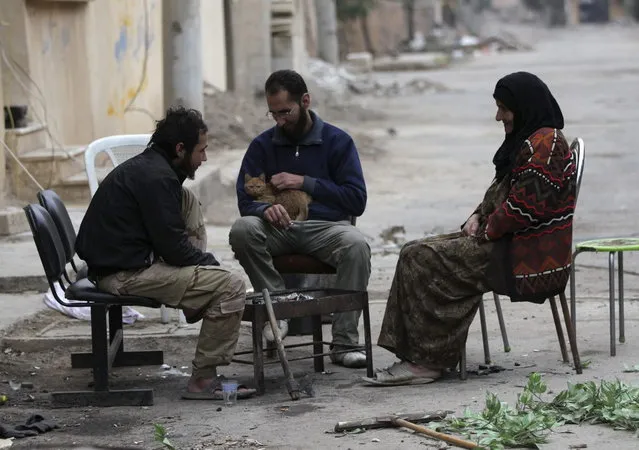 A “Free Syrian Army” fighter pats a cat as he sits with a fellow fighter and an elderly woman in Deir al-Zor, eastern Syria December 4, 2013. (Photo by Khalil Ashawi/Reuters)