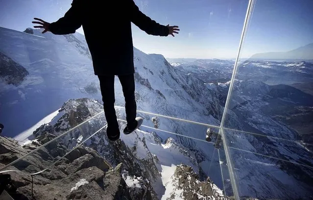 A journalist, wearing slippers to protect the glass floor, stands in the “Step into the Void” installation during a press visit at the Aiguille du Midi mountain peak above Chamonix, in the French Alps, on December 17, 2013. (Photo by Robert Pratta/Reuters)