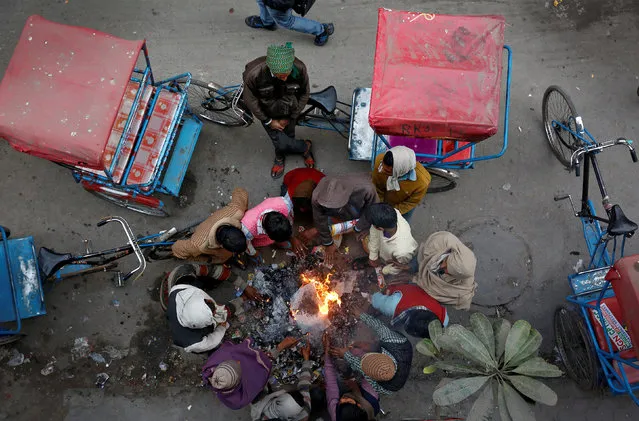 Rickshaw drivers heat themselves around a fire of burning garbage in Delhi, India January 11, 2017. (Photo by Cathal McNaughton/Reuters)