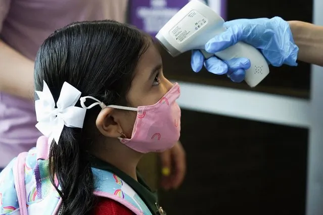 Pre-K student Penelope has her temperature checked before entering Benbrook Elementary School on the first day of school in Houston, Texas, August 23, 2021. (Photo by Go Nakamura/Reuters)