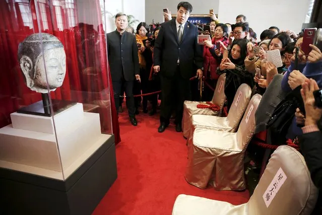 People take pictures of the head of a Buddha statue that is some 1500 year old, moments after it was presented at the National Museum of China in Beijing Match 1, 2016. The head of an antique statue, that was stolen 20 years ago from a temple in Hebei province and taken abroad, was returned from Taiwan to China by Buddhist master Hsing Yun, local media reported. (Photo by Damir Sagolj/Reuters)