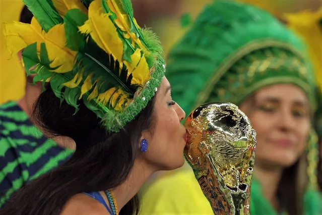 A Brazil supporter kisses a replica of the world cup trophy before the Qatar 2022 World Cup quarter-final football match between Croatia and Brazil at Education City Stadium in Al-Rayyan, west of Doha, on December 9, 2022. (Photo by Adrian Dennis/AFP Photo)