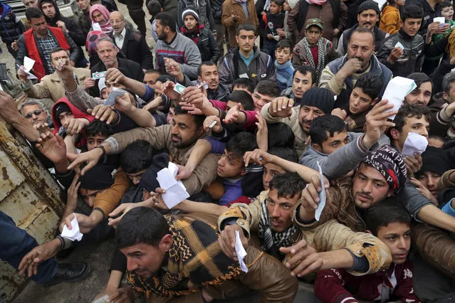 Civilians present their rations cards in order to receive humanitarian food aid being distributed by the Iraqi Red Crescent, in the eastern side of Mosul, Iraq, Tuesday, January 31, 2017. Iraqi forces declared Mosul's eastern half fully liberated, just over three months after the operation to retake the city from IS was formally launched in October. (Photo by Khalid Mohammed/AP Photo)