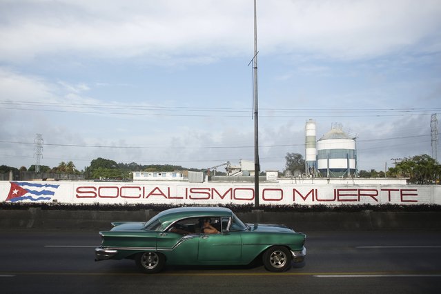 A vintage car moves past a wall mural that reads “Socialism or Death” in Havana, Cuba March 20, 2016. (Photo by Alexandre Meneghini/Reuters)
