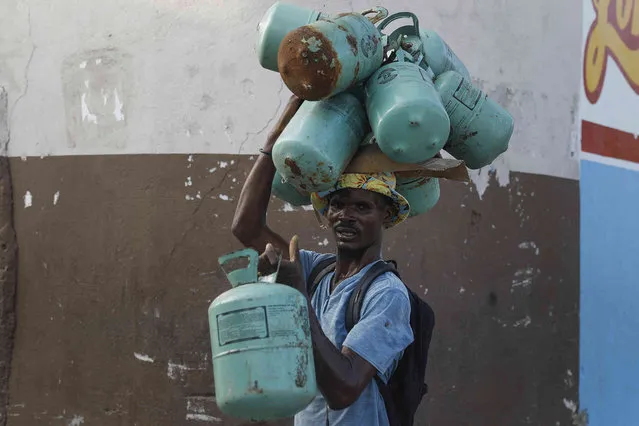 A man walks past balancing empty gas canisters on his head, in Port-au-Prince, Haiti, Wednesday, October 27, 2021. (Photo by Joseph Odelyn/AP Photo)