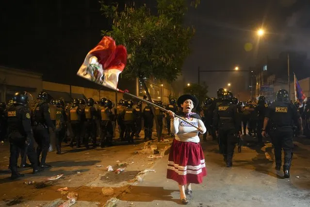 A woman waves a Peruvian flag during an anti-government protest in Lima, Peru, Friday, January 20, 2023. Protesters are seeking the resignation of President Dina Boluarte, the release from prison of ousted President Pedro Castillo and immediate elections. (Photo by Guadalupe Pardo/AP Photo)