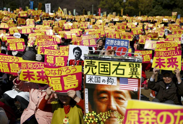 People hold placards with anti-nuclear energy slogans during No Nukes Day, a protest calling for a nuclear-free future in Yoyogi park in Tokyo, Japan, March 26, 2016. The writing above the picture of Japan's Prime Minister Shinzo Abe reads, “Right Wing Sell-Out Nation” and “America's Dog”. (Photo by Thomas Peter/Reuters)