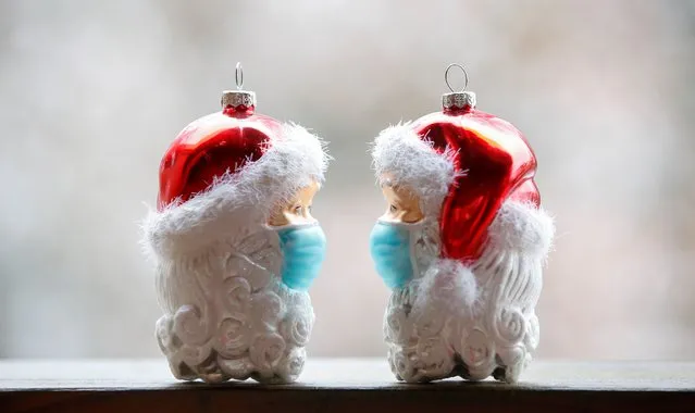Christmas baubles shaped as Santa Clauses wearing protective masks are pictured amid the coronavirus disease (COVID-19) pandemic in Eichenau, Germany, November 26, 2021. (Photo by Michaela Rehle/Reuters)