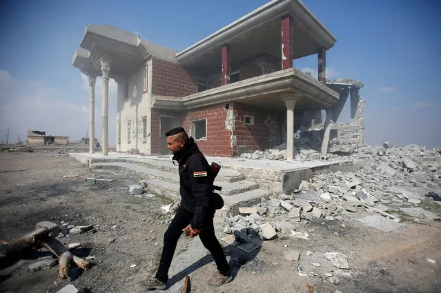 A Sunni Arab fighter walks near a house, which the residents of the village said belonged to a man who joined the Islamic State militants and was destroyed in an explosion, in Rfaila village in the south of Mosul, Iraq, February 17, 2017. (Photo by Khalid al Mousily/Reuters)