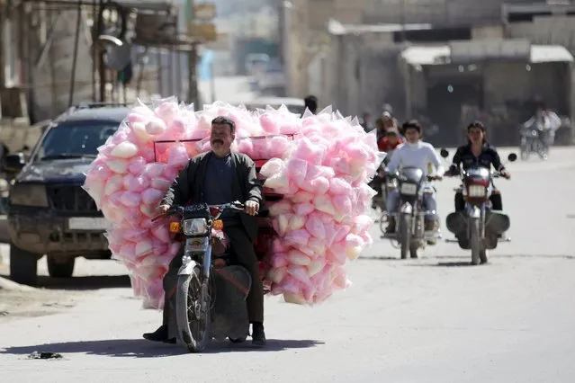 A man rides a motorbike as he sells cotton candy along a street in the rebel-controlled area of Maaret al-Numan town in Idlib province, Syria April 1, 2016. (Photo by Khalil Ashawi/Reuters)