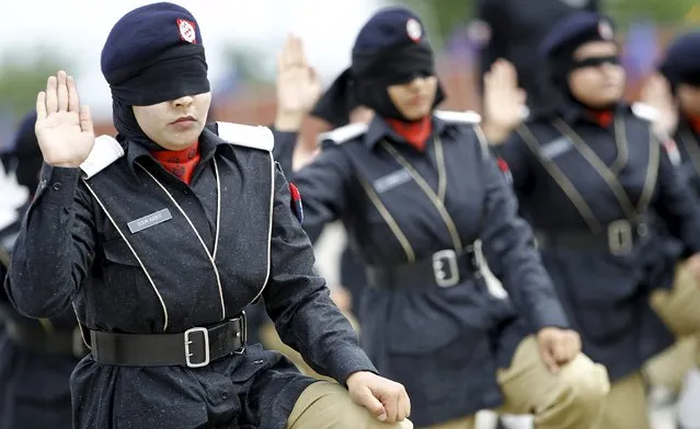 Police academy graduates signal the completion of their weapon disassembly and assembly while being blindfolded, during their graduation ceremony in Islamabad, Pakistan May 18, 2015. (Photo by Caren Firouz/Reuters)