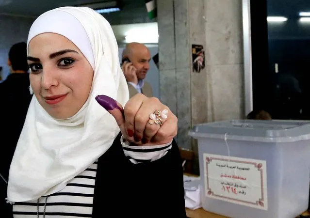 A Syrian woman shows her ink stained thumb after voting at a polling station during parliamentary elections in Damascus on April 13, 2016. Polls opened in areas of war torn Syria controlled by President Bashar al-Assad, for a vote that will not be recognised by the United Nations and has been dismissed by regime opponents as illegitimate. (Photo by Joseph Eid/AFP Photo)
