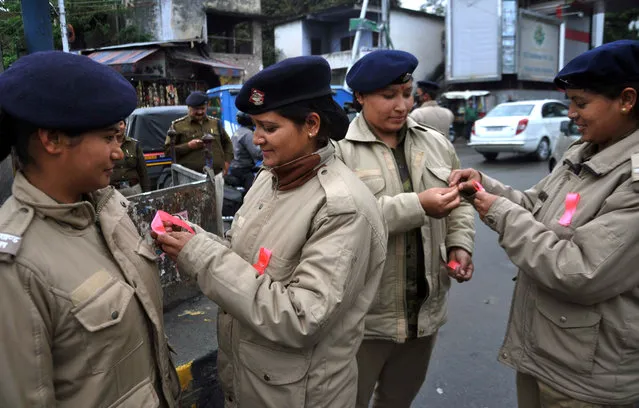 Indian policewomen tie ribbons onto each others uniforms in Dehradun on March 8, 2017, as they mark International Women' s Day. (Photo by AFP Photo/Stringer)