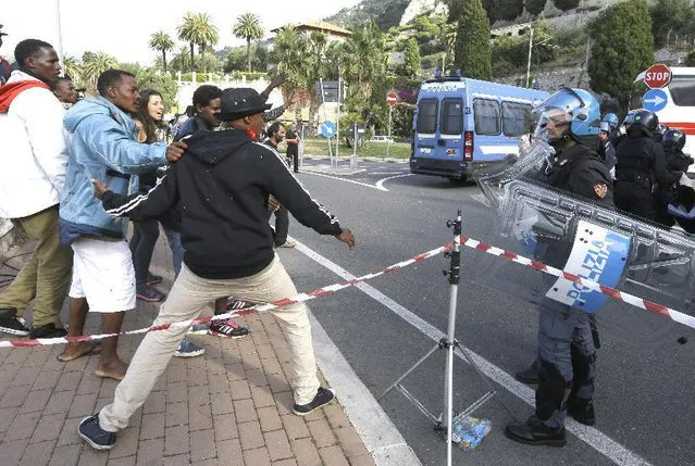 Italian policemen stand in front of migrants at the Franco-Italian border near Menton, southeastern France, Tuesday, June 16, 2015 in their attempt to evacuate them. Some 150 migrants, principally from Eritrea and Sudan, have been trying since last Friday to cross the border from Italy but have been blocked by French and Italian police. (AP Photo/Lionel Cironneau)