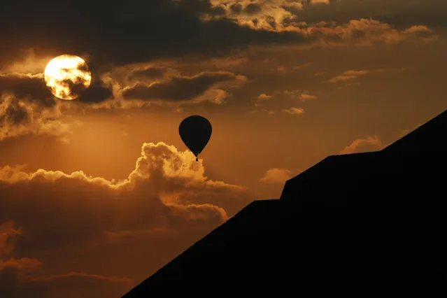 In this Thursday, March 21, 2019 photo, a balloon flies near the Pyramid of the Sun as the sun rises in Teotihuacan, Mexico, on the Spring equinox. (Photo by Marco Ugarte/AP Photo)