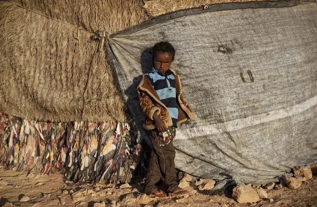 In this photo taken Thursday, March 9, 2017, a boy who fled the drought stands next to the makeshift hut where he sleeps in a camp for the displaced in Qardho in Somalia's semiautonomous northeastern state of Puntland. (Photo by Ben Curtis/AP Photo)