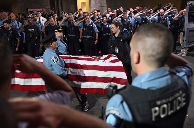 Law enforcement officers salute the flag-draped remains of fallen Minneapolis police Officer Jamal Mitchell as he is escorted to a waiting medical examiner's vehicle outside Hennepin County Medical Center in Minneapolis, Thursday, May 30, 2024. Mitchell was killed earlier in the day while responding to a shooting call. (Photo by Aaron Lavinsky/AP Photo)