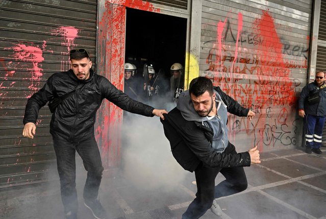 Workers of the tourism sector escape tear gas at the entrance of the Ministry of Labour and Social Affairs in Athens, Greece, as they demonstrate to call for their rights and better payment ahead of the tourism season, on February 22, 2023. (Photo by Louisa Gouliamaki/AFP Photo)