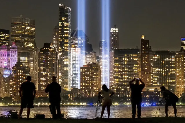 Spectators and photographers look across the Hudson River from Jersey City, N.J., at the Sept. 11 tribute lights in New York City on the 18th anniversary, Wednesday, September 11, 2019, of the attacks on the twin towers of the World Trade Center. (Photo by J. David Ake/AP Photo)