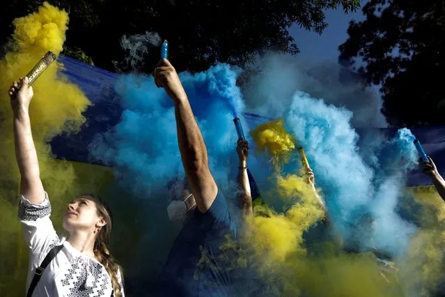 People hold flares with the colors of the Ukrainian flag as Ukrainians and supporters hold an anti-war protest outside the Russian Embassy, following Russia's invasion of Ukraine, in Mexico City, Mexico on February 28, 2022. (Photo by Luis Cortes/Reuters)