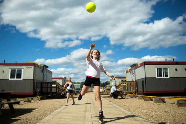 Emma VanDuinkerken tosses a ball with new friends at a camp in Wandering River after evacuating Fort McMurray, Alberta, Canada, due to raging wildfires on May 8, 2016. (Photo by Topher Seguin/Reuters)