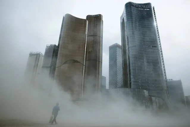 A man walks through a cloud of dust whipped up by wind at the construction site near newly erected office skyscrapers in Beijing, China April 20, 2017. (Photo by Thomas Peter/Reuters)