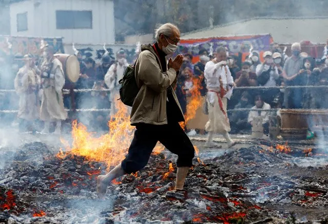 A man walks next to flame as he walks over coal with barefoot at the fire-walking festival, called Hiwatari Matsuri in Japanese, at Mt.Takao in Tokyo, Japan, March 13, 2022. About 1,500 Japanese worshipers walk barefoot with Buddhist monks over coals at the annual festival praying for the safety of themselves, to overcome the coronavirus disease (COVID-19) pandemic and for peace in the world, Takao-san Yakuo-in Buddhist temple said. (Photo by Kim Kyung-Hoon/Reuters)