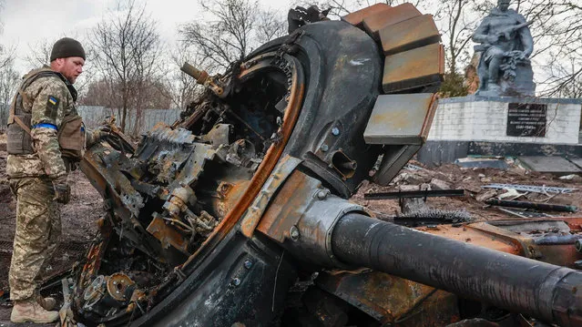 A Ukrainian soldier inspects the remains of a destroyed Russian tank in the recently liberated village of Lukyanivka in the Kyiv region on March 27, 2022. (Photo by Serhii Nuzhnenko/Radio Free Europe/Radio Liberty)