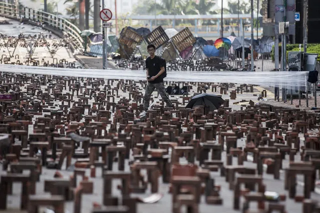 A man (C) walks through bricks placed on a barricaded street outside The Hong Kong Polytechnic University in Hong Kong on November 15, 2019. Pro-democracy protesters challenging China's rule of Hong Kong on November 14 choked the city for a fourth straight working day, firing arrows at police, barricading roads and disrupting transport links, as schools and businesses closed. (Photo by Isaac Lawrence/AFP Photo)