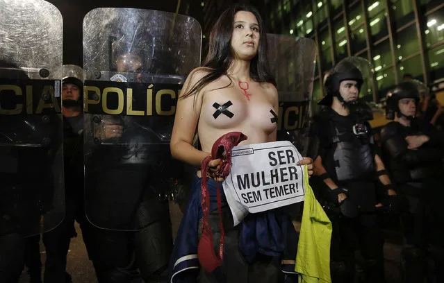 A woman with a sign that reads in Portuguese “Being woman without Temer”, stands next to a police barricade during a protest against the gang rape of a 16-year-old girl in Sao Paulo, Brazil, Wednesday, June 1, 2016. In response to the assault, Brazil's interim President Michel Temer said that the country will set up a specialized group to fight violence against women. (Photo by Andre Penner/AP Photo)