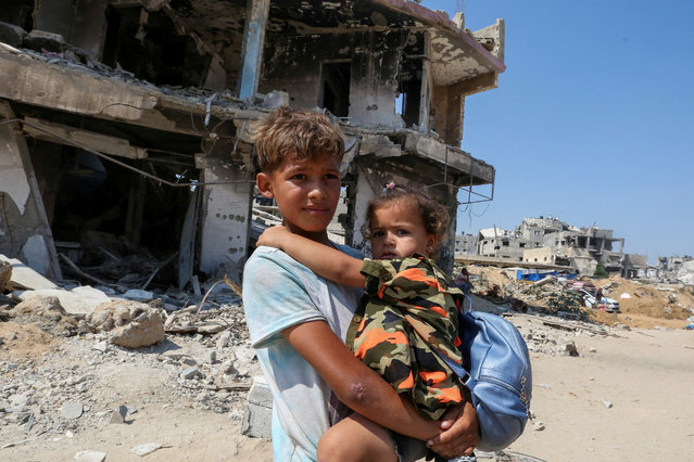 A Palestinian boy holds a girl as they flee the eastern part of Khan Younis to make their way after they were ordered by Israeli army to evacuate their neighborhoods, amid Israel-Hamas conflict, in Khan Younis in the southern Gaza Strip on July 22, 2024. (Photo by Hatem Khaled/Reuters)