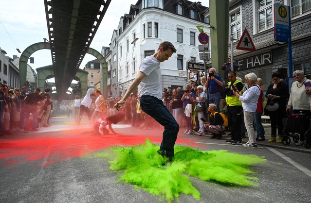 Around 200 dancers, amateurs and professionals, perform together on Sonnborner Strasse under the route of the suspension railroad “Schwebebahn” during a happening of the Tanztheater Wuppertal Pina Bausch in Wuppertal, western Germany, on May 21, 2023. Boris Charmatz has been artistic director of the Tanztheater Wuppertal Pina Bausch for nine months. Now the French dancer is about to introduce his ideas with a whole series of events and performances, among others “Wundertal”, which will take place from May 21 to May 29, 2023 at various locations indoors and outdoors in the western German city of Wuppertal. (Photo by Ina Fassbender/AFP Photo)