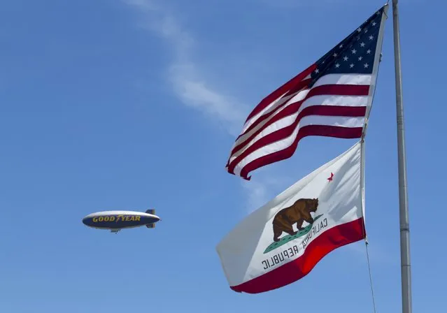 The Goodyear blimp “Spirit of America” flies past flags in Carson, California August 5, 2015. (Photo by Mike Blake/Reuters)