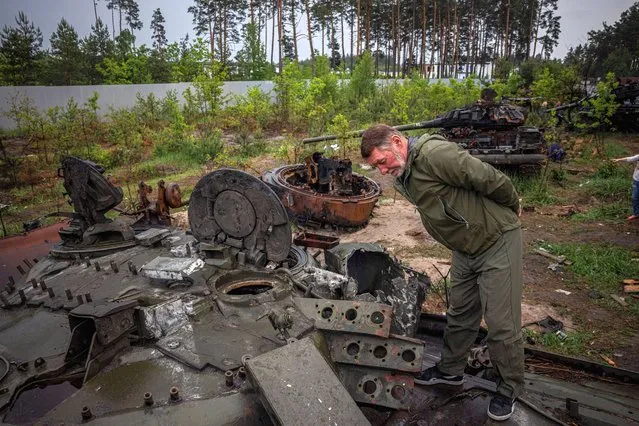 A local resident examines a destroyed Russian tank outside Kyiv on May 31, 2022, amid the Russian invasion of Ukraine. (Photo by Dimitar Dilkoff/AFP Photo)