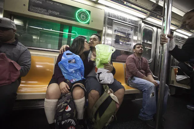 A couple kisses as they ride the 6 train in the Bronx borough of New York October 27, 2014. (Photo by Carlo Allegri/Reuters)